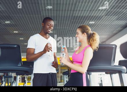 Freunde teilen sich in einem Fitnessstudio Getränke und genießen nach dem gemeinsamen Workout eine Pause Stockfoto