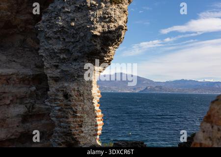 Blick auf den Gardasee und die Berge durch antike Steinruinen in Sirmione, Lombardei, Norditalien. Stockfoto