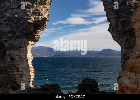 Blick auf den Gardasee und die Berge durch antike Steinruinen in Sirmione, Lombardei, Norditalien. Stockfoto