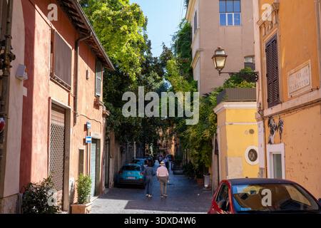 Rom Italien - 3. Oktober 2022: Die Menschen laufen in Rom Italien auf einer schmalen Straße, die von üppigen Pflanzen überflutet ist Stockfoto