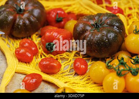 Bunte Tomatenmischung mit Messer und wiederverwendbarem Netzbeutel für umweltfreundliches Kochen Stockfoto