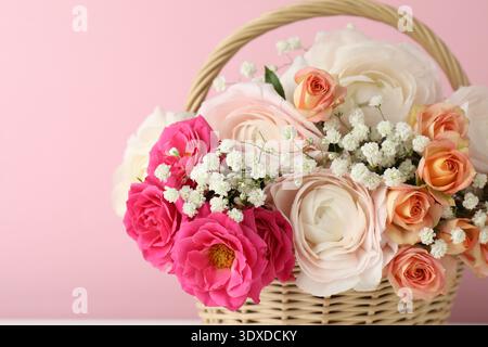 Schöne Blumen im Korb auf rosa Hintergrund, Nahaufnahme Stockfoto