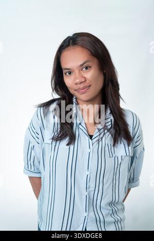 Einfaches Porträt einer freundlichen indonesischen Frau in einem gestreiften Hemd. Klare Studioaufnahme für Identität, Mitarbeiterprofil und lässige asiatische Lifestyle-Konzepte. Stockfoto