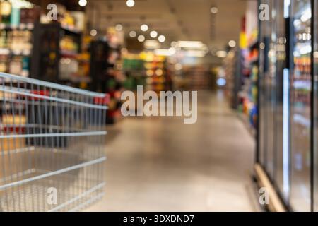 Verschwommener Supermarktgang mit Einkaufswagen im Fokus, modernes Innenleben mit warmem Bokeh-Licht, Konsumverhalten im Einzelhandel und Food Shopping Co Stockfoto