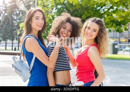 Drei Freunde posieren zusammen in einer sonnigen Outdoor-Umgebung, in der Happy Moments und Freundschaft präsentiert werden Stockfoto