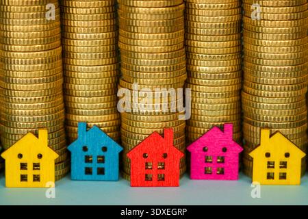 Bunte Miniaturhäuser vor dem Münzstapel Immobilieninvestitionskonzept Stockfoto