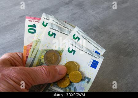 Die Hand hält Euro-Banknoten und -Münzen und schließt das europäische Geld- und Finanzkonzept Stockfoto