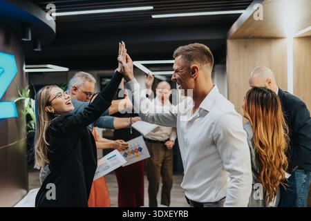 Bürofeier mit Kollegen, die den Erfolg des Teams in einem lebhaften Treffen am Arbeitsplatz feiern Stockfoto