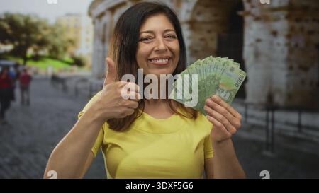 Die Frau im Mittelalter zeigt chilenische Peso-Banknoten mit Daumen nach oben beim Bau am kolosseum; Vertrauen in die Tourismusfinanzierung. Stockfoto