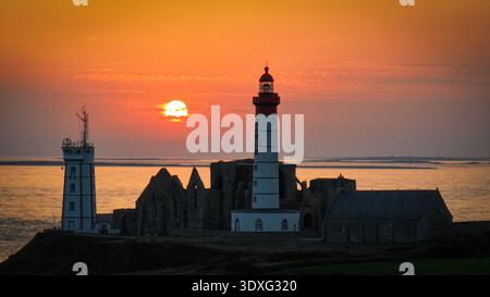 Aus der Vogelperspektive auf die Silhouette des Leuchtturms Phare de Saint-Mathieu und die Ruinen einer Kapelle vor einem orangen Sonnenuntergang, Plougonvelin, Bretagne, Frankreich. Stockfoto