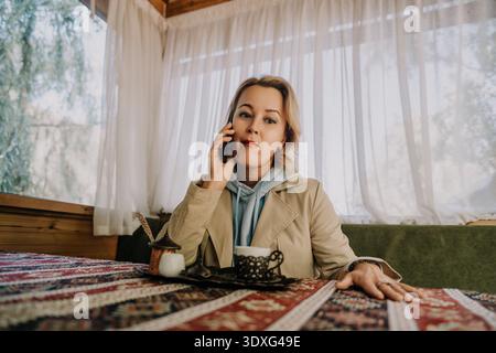 Frau am Telefon in einem gemütlichen Café Stockfoto