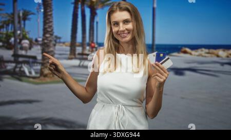 Frau, die Kreditkarte hält und mit dem Finger zeigt, während sie lächelt und mit Karten auf der Straße Hand zeigt; Selbstvertrauen bei der Reiseplanung. Stockfoto