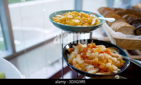 Bunte Obstplatten, darunter getrocknete Aprikosen, gewürfelte Ananas, Orangenscheiben, Grapefruit, und grüne Äpfel, auf einem Buffettisch angeordnet Stockfoto