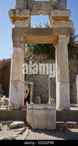 Junge Frau, die in einem offenen antiken Gebäude in ephesus, türkei, steht und auf Marmorruinen blickt; Geschichte bewundert. Stockfoto