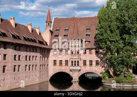 Das Krankenhaus Heilig Geist befindet sich an der Pegnitz in der Nürnberger Altstadt und bietet mittelalterliche Architektur mit roten Ziegeldächern und Bogenfenstern. Stockfoto