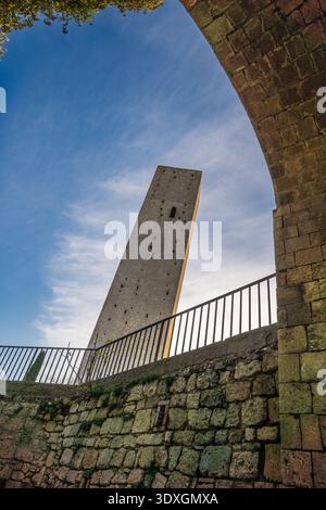 Ein Niedrigwinkelfoto, das die Majestät der Santa Maria im Castello Tower in Tarquinia einfängt. Eingerahmt von einem alten Bogengang hebt das Bild den Volumenkörper hervor Stockfoto