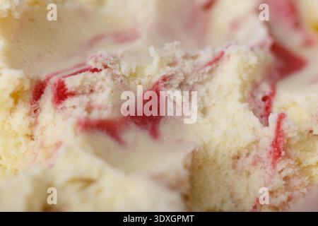 Makroaufnahme von cremigem Vanilleeis mit Himbeer-variegato-Wirbeln, mit glatter Textur und Kräuselung roter Früchte. Abstraktes gefrorenes Dessert zurück Stockfoto