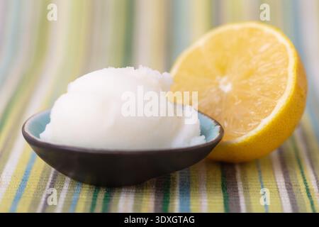 Ein Messlöffel erfrischendes Zitronensorbet, serviert mit einer halben Zitrone Stockfoto