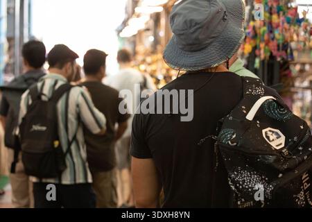 Mann-Rucksack, der durch den Außenmarkt läuft, örtlicher Straßenhandel, thailändischer Wochenendmarkt Lifestyle, Rückansicht, am Chatuchak Markt. Stockfoto