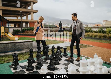 Geschäftspartner planen beim Freiluftschach auf einem riesigen Brett im Park ihre Strategie Stockfoto