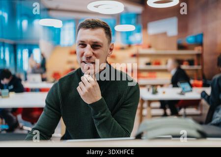 Geschäftsmann in einem modernen Großraumbüro, posiert nachdenklich an einem Schreibtisch für Stockfotos Stockfoto