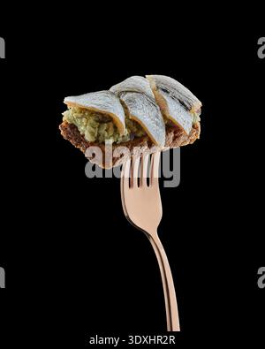 Offenes Sprotte-Sandwich mit Roggenbrot, Eiersalat und Fisch ausgewogen auf Gabel isoliert auf schwarzem Hintergrund. Stockfoto
