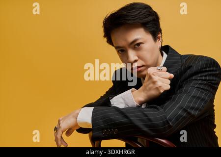 Ein junger asiatischer Geschäftsmann posiert selbstbewusst in einem eleganten Anzug im Studio Stockfoto