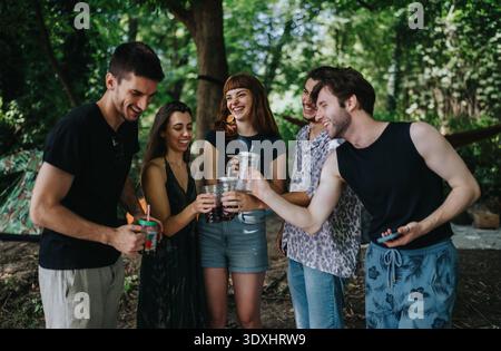 Gruppe von Freunden, die in einem Park Getränke trinken, lächeln und ein Treffen im Freien genießen Stockfoto
