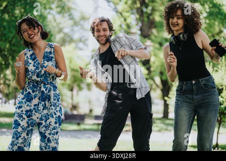 Drei Freunde tanzen im Park und genießen gemeinsam einen sonnigen Tag Stockfoto