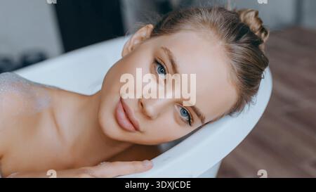 Frau genießt ein Blasenbad in einer weißen Badewanne mit entspanntem Ausdruck Stockfoto