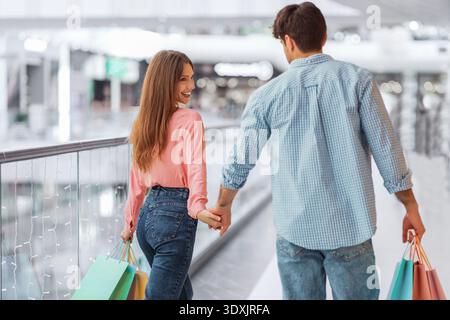 Ein Paar geht Hand in Hand, während es abends in einer Mall einkaufen geht Stockfoto