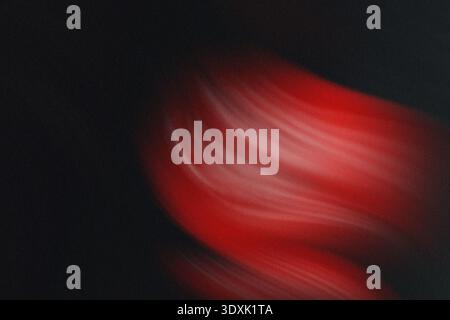 Abstraktes, unscharfes Bild in leuchtendem Rot mit Anklängen an grüne und dunkle Hintergrundelemente Stockfoto