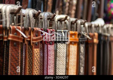 Verschiedene strukturierte Ledergürtel hängen auf dem Ausstellungsregal auf dem Markt Stockfoto