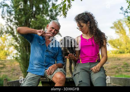Porträt von Hundetrainer von Vater und Tochter, die zusammen mit einem italienischen Schäferhund Lagorai auf einem Holztisch in einem öffentlichen Park sitzen Stockfoto