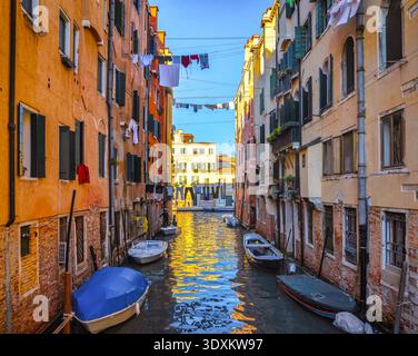 Wäsche hängt über einem schmalen Kanal, der von farbenfrohen Häusern und Booten gesäumt ist, Cannaregio, Venedig, Italien Stockfoto