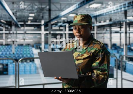 Weibliche Expertin für Informationstechnologie der Armee in Rechenzentren bei der Fehlersuche von militärischen Computersystemen und Netzwerken mit Laptop. Soldat im Kommandozentrum-Server-Hub mit Notebook Stockfoto