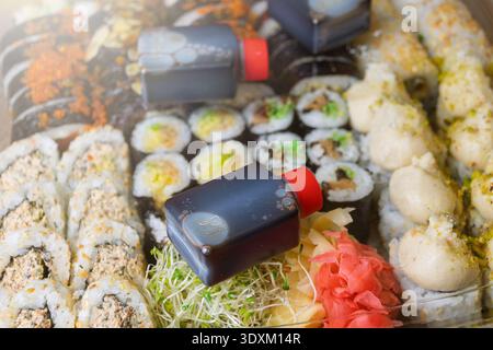 Verschiedene Sushi-Tabletts mit Soßenflasche und Beilagen. Vegane Sushi-Brötchen. Stockfoto