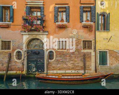 Holzboot, das an einem verzierten, mit Blumen geschmückten Kanalhause festgemacht ist, Cannaregio, Venedig, Italien Stockfoto