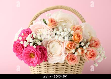 Schöne Blumen im Korb auf rosa Hintergrund, Nahaufnahme Stockfoto