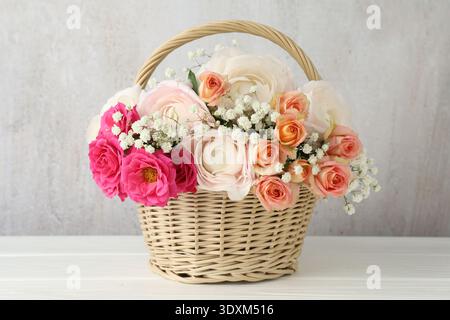 Schöne Blumen im Korb auf weißem Holztisch Stockfoto