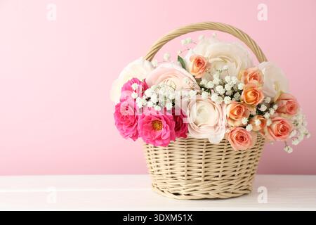 Schöne Blumen im Korb auf weißem Holztisch. Leerzeichen für Text Stockfoto