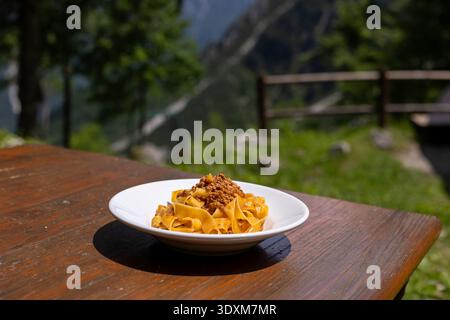 Hausgemachte Tagliatelle mit Hackfleisch ragù wird in einem weißen Gericht auf einem rustikalen Holztisch serviert. Die Einstellung scheint sich in der Nähe des zu befinden Stockfoto