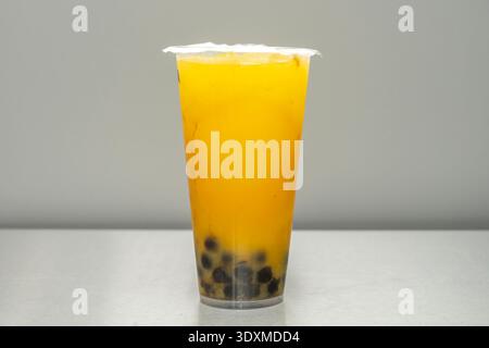 Ein Teegetränk aus Mango-Bubble mit echten Fruchtstücken am Boden und einer halbfesten Textur Stockfoto