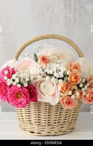 Schöne Blumen im Korb auf weißem Holztisch Stockfoto