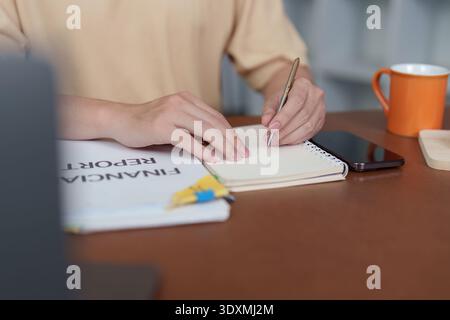 Notizen machen. Nahaufnahme eines jungen Mannes, der im Heimbüro in Notizbuch schreibt. Stockfoto