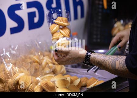 BANGKOK, THAILAND-4. Februar 2026: Männlicher Verkäufer arrangiert Snacks in Plastiktüte, Südostasien reist aufrichtige Leute, Nahaufnahme, auf dem Wang lang Market. Stockfoto