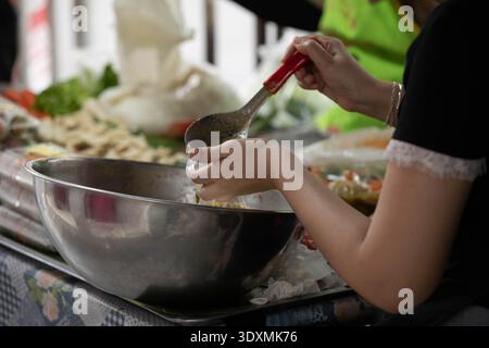 Weibliche Verkäuferin, die Lebensmittel in Plastiktüte für Kunden, lokale Händler Street Commerce, dynamisches Straßenleben, Nahaufnahme, auf dem Wang lang Market. Stockfoto
