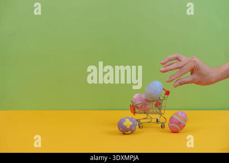 SSTK Ostern. Die Hand greift nach pastellfarbenen Ostereiern im Warenkorb. Stockfoto