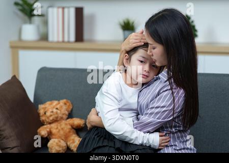 Mutter tröstet krankes Kind zu Hause. Emotionale Unterstützung und Betreuung. Stockfoto
