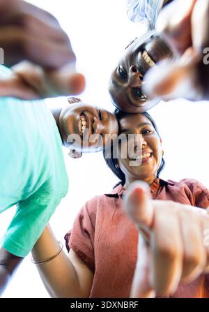 Vielfältige Familie mit Teenagern, die sich hineinlehnen, lächeln, Hände zur Kamera greifen, Armband gesehen Stockfoto